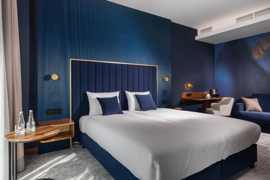a bedroom with a large bed and a blue wall at My Story Gdynia Hotel in Gdynia