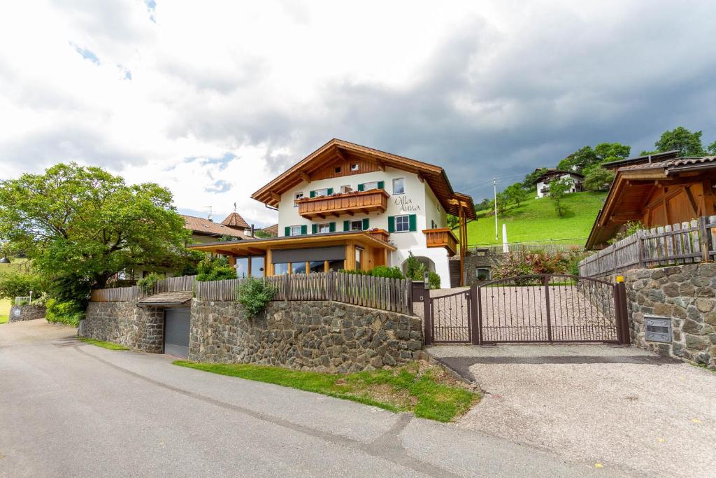 a house with a stone wall and a fence at Villa Anna in Siusi