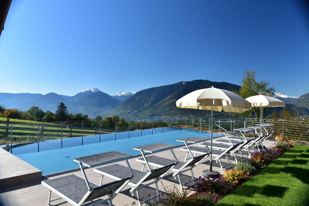 思科納的住宿－Residence Krone，一个带椅子和遮阳伞的游泳池,背景为山脉