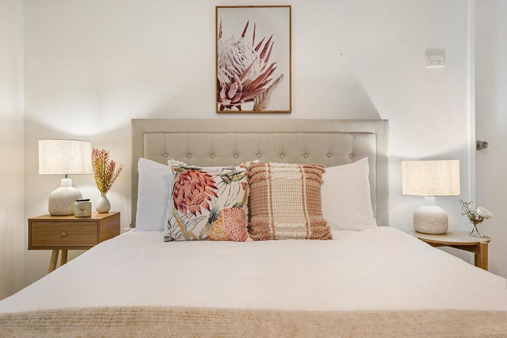 a bedroom with a white bed with pillows and two lamps at Spacious Family Beach House in Caloundra