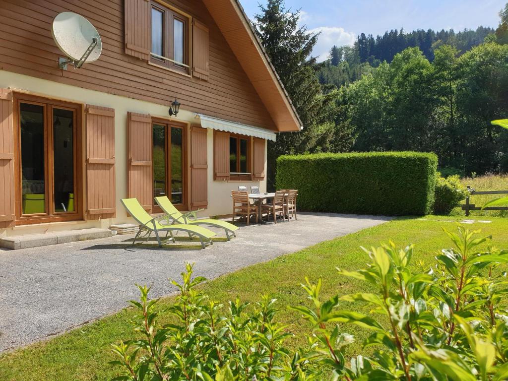 une maison avec un patio avec des chaises et une table dans l'établissement LE BOIS JOLI Chalet 4 étoiles CLEDICIHOME Cadre paisible en lisière de forêt, à Gérardmer