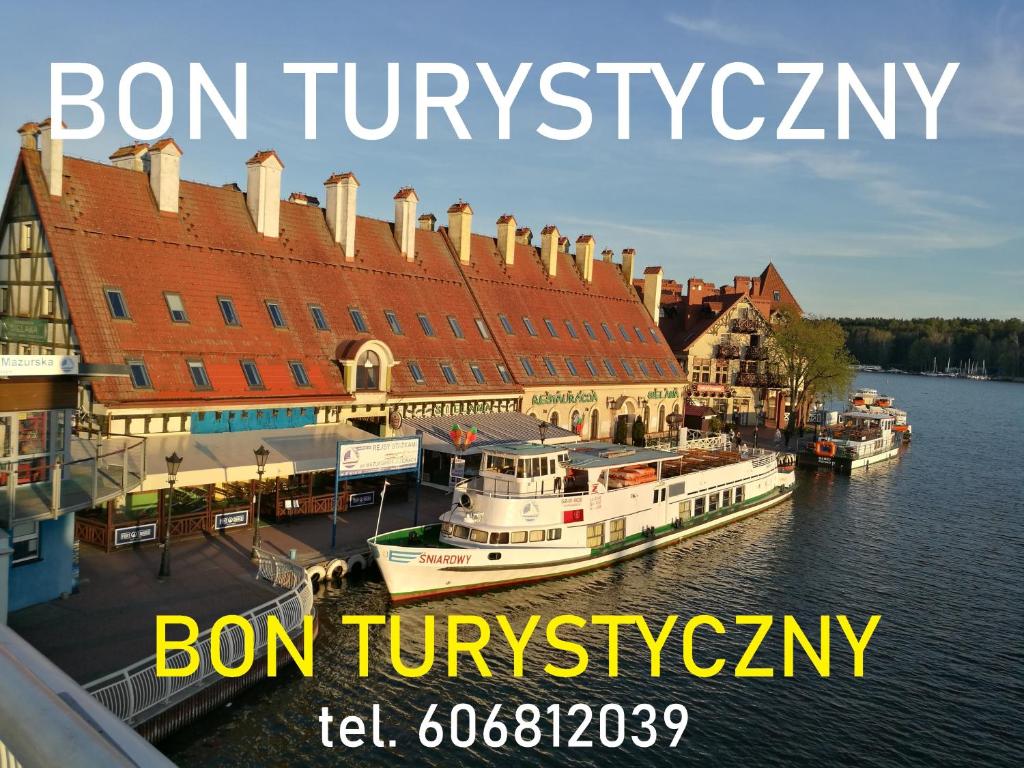 Znak z napisem "bon tivoliatown with boat in the water" w obiekcie Apartamenty Sielawa w mieście Mikołajki