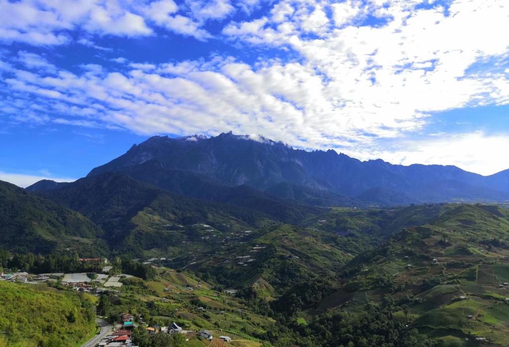 una vista a la montaña de un valle con un cielo nublado en D' Limbai Cottage en Ranau