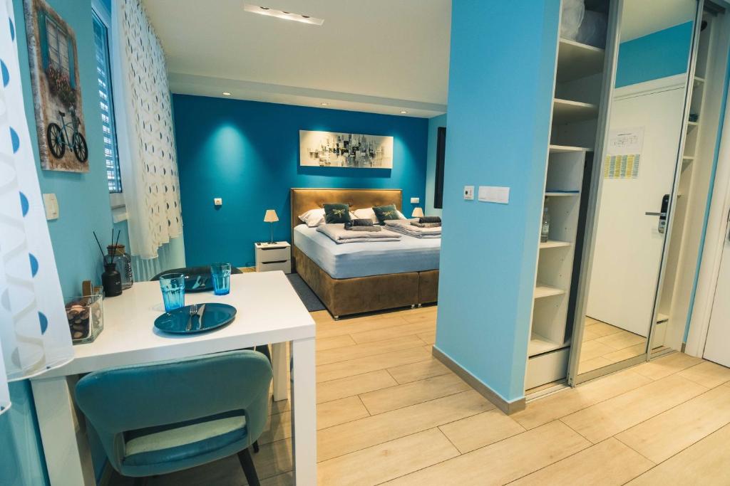 um quarto azul com uma cama, uma secretária e uma mesa em The Place Apartments Hebrangova em Zagreb