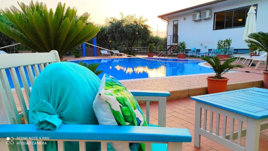 a person sitting on a blue bench in front of a pool at Medimare Residence Club in Patti