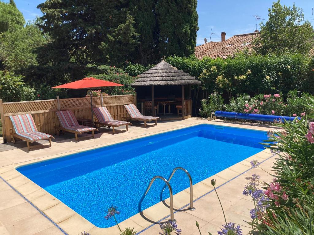 a swimming pool with chairs and a gazebo at Maison Oleander in Bize-Minervois