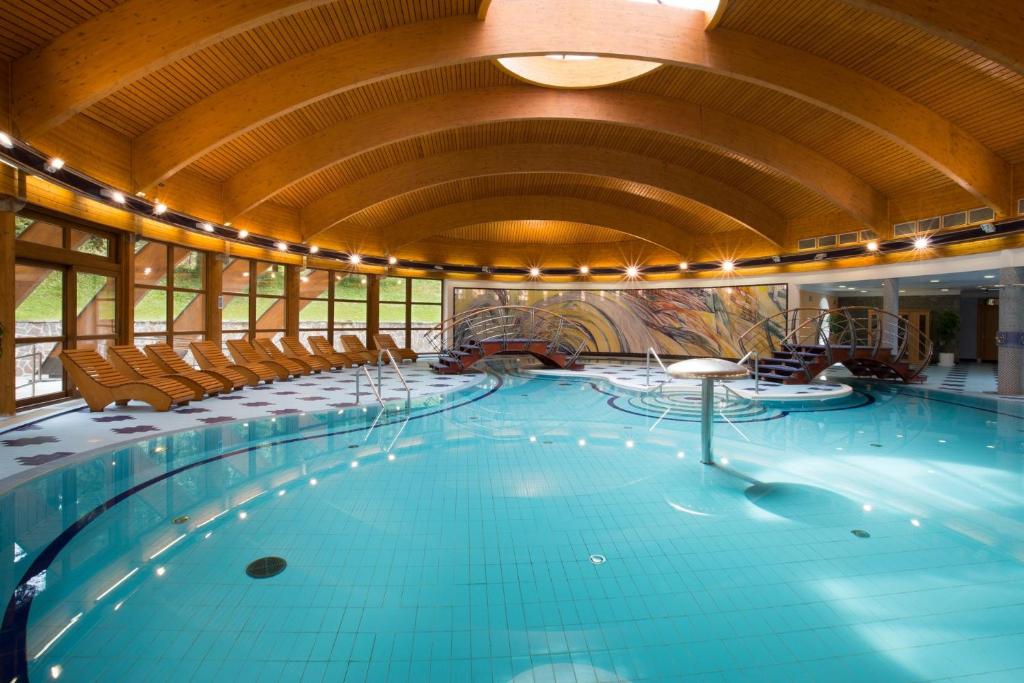 a large swimming pool with chairs and a ceiling at Rezidence Klínovec in Loučná pod Klínovcem