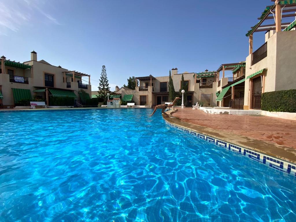 a person jumping into a large blue swimming pool at Tu Casa in Puerto de Mazarrón