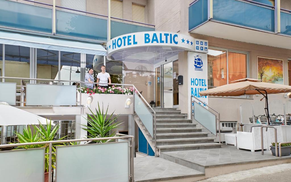 dos personas de pie en un balcón de un edificio de hotel en Hotel Baltic en Gabicce Mare
