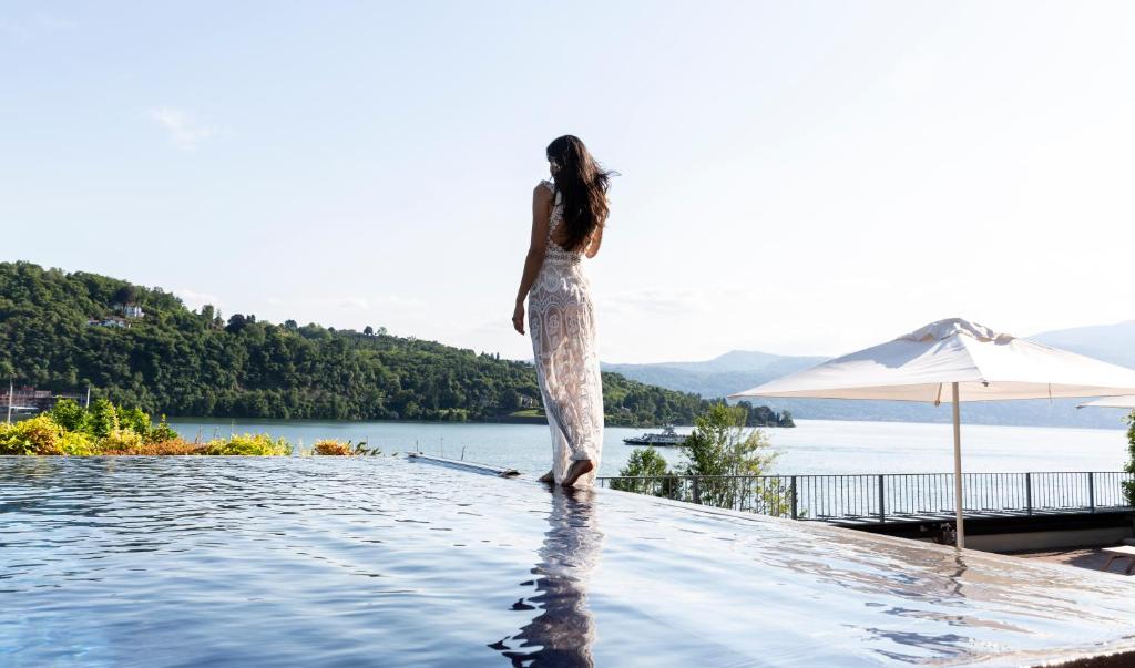 a woman standing on top of a boat in the water at Hotel de Charme Laveno in Laveno-Mombello