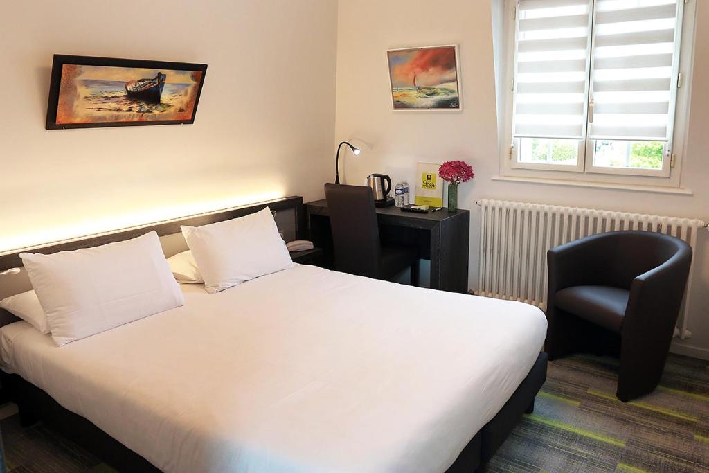 - une chambre avec un lit, un bureau et une chaise dans l'établissement Logis Le Prieuré, à Locronan