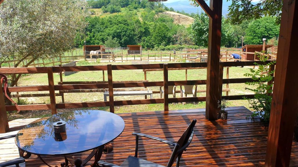 a table and chairs on a deck with a view of a field at Chambre d'hôtes le petit Ranch in Los Masos