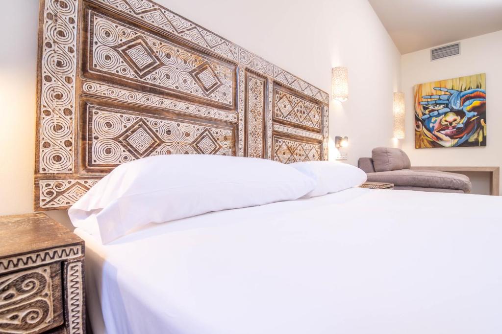 1 dormitorio con cama blanca y cabecero de madera en Tarifa Suites by QHotels, en Tarifa