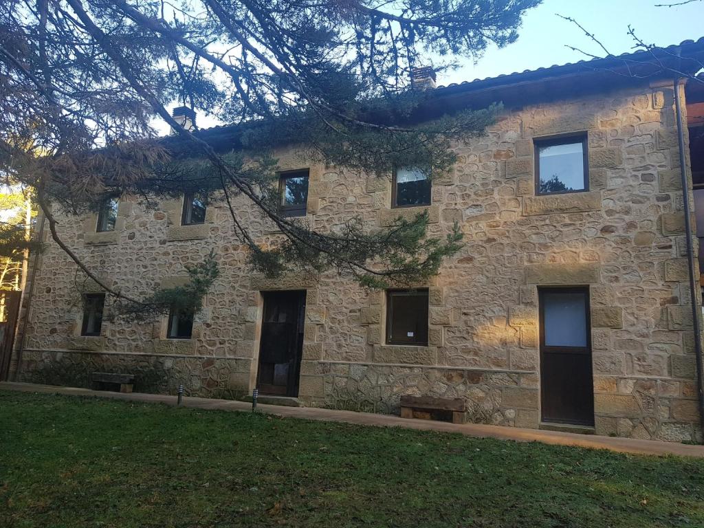 un edificio de piedra con ventanas y un árbol en Casa Rural Laguna Negra, en Vinuesa