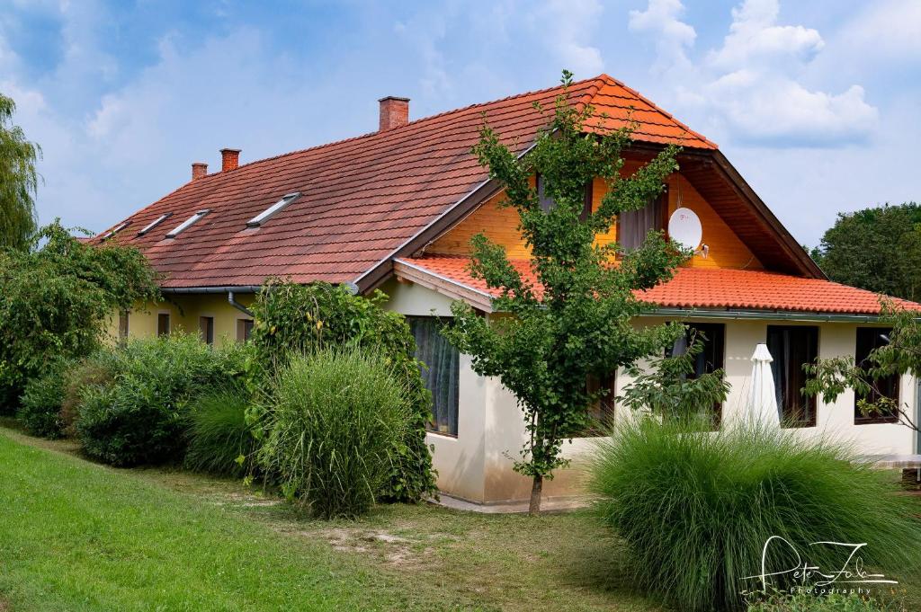 una casa con techo naranja y algunos arbustos en Tókert Vendégház, en Őriszentpéter