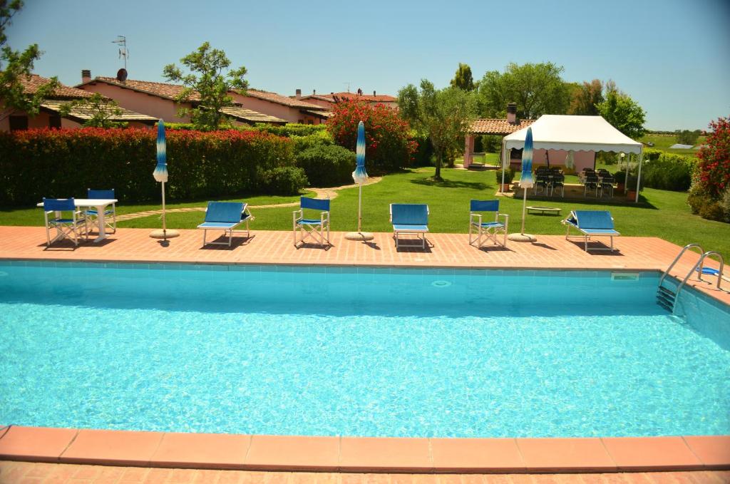a swimming pool with chairs and a gazebo at Agriturismo Le Grazie in Principina Terra