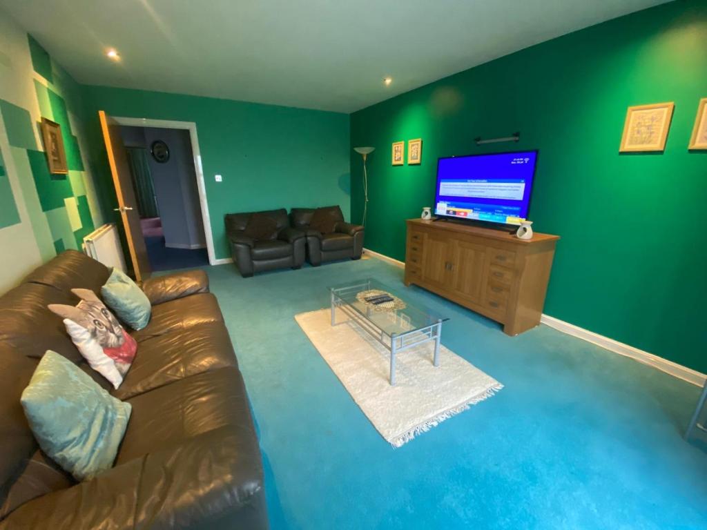 ein Wohnzimmer mit einem Sofa und einem Flachbild-TV in der Unterkunft Comfortable, self contained 2 double beds town apartment near Pittodrie Stadium in Aberdeen