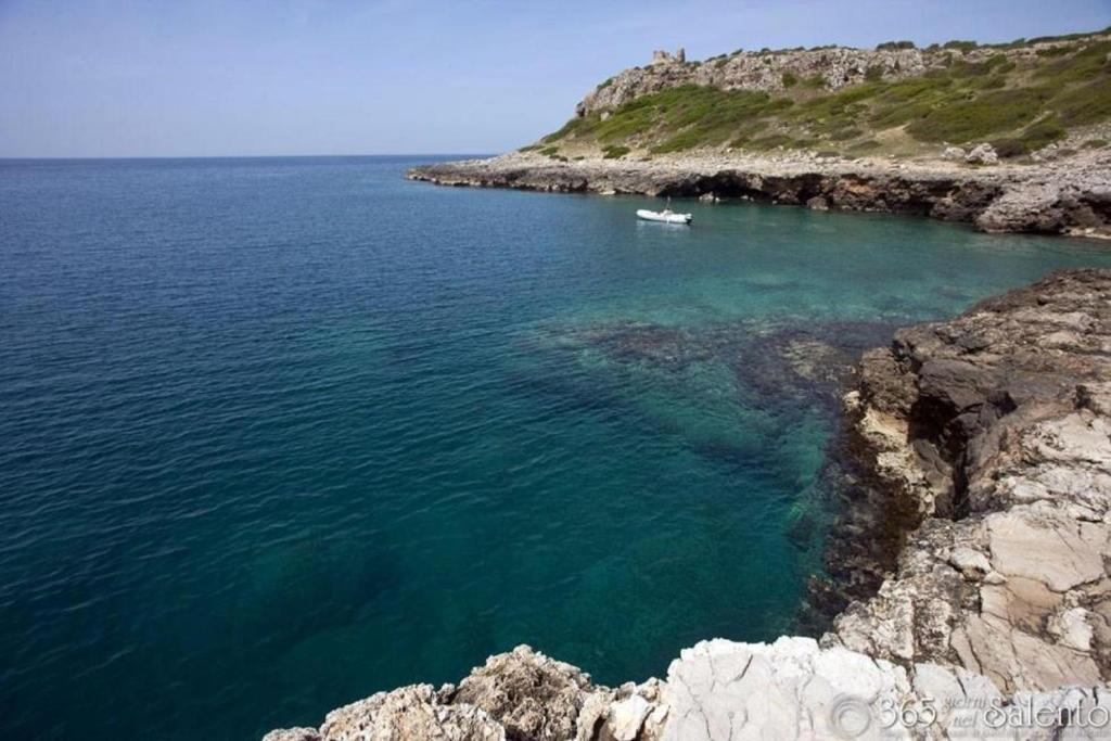 a boat in the water next to a rocky shore at Santa Caterina Resort in Santa Caterina di Nardò