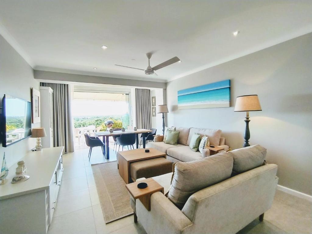a living room with a couch and a table at Sara's Upmarket Apartment - Lagoon Views, Patio, Braai & WIFI & DSTV in Plettenberg Bay