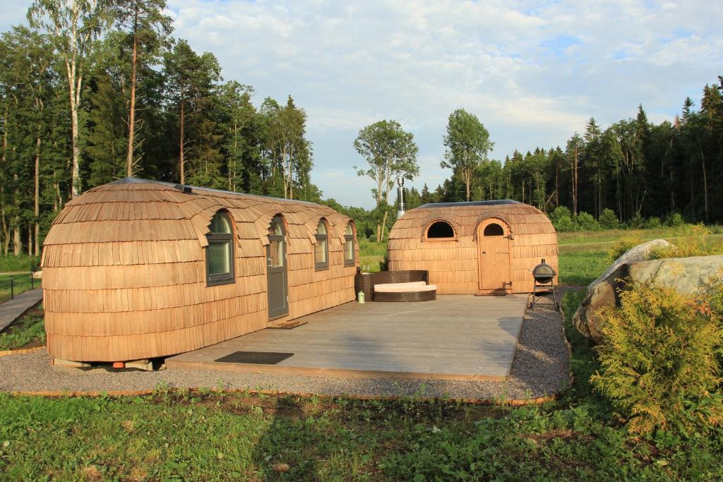 Kuldallika igloo house and iglusauna في Kullamäe: بضعة مباني خشبية كبيرة في حقل