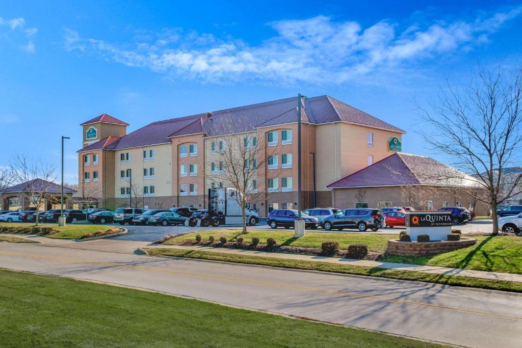 un grand bâtiment avec des voitures garées dans un parking dans l'établissement La Quinta by Wyndham Indianapolis Airport West, à Plainfield