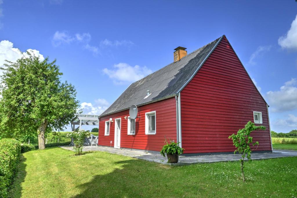 une grange rouge avec un toit noir sur un champ dans l'établissement fewo1846 - Rotes Haus - idyllisch gelegenes Haus mit 2 Schlafzimmern und großem Grundstück, à Husby