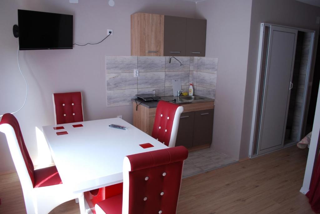 a kitchen with a white table and red chairs at Apartmani ,studija i sobe Savić in Soko Banja