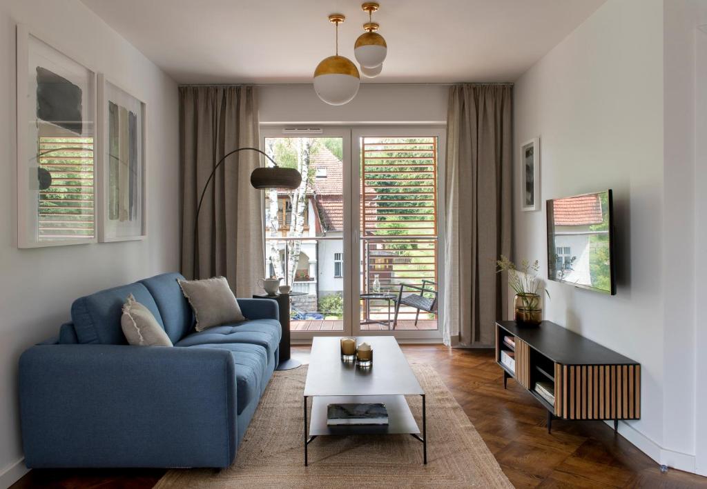 salon z niebieską kanapą i stołem w obiekcie Apartament LUMOS by Pedro Polanica w Polanicy Zdroju