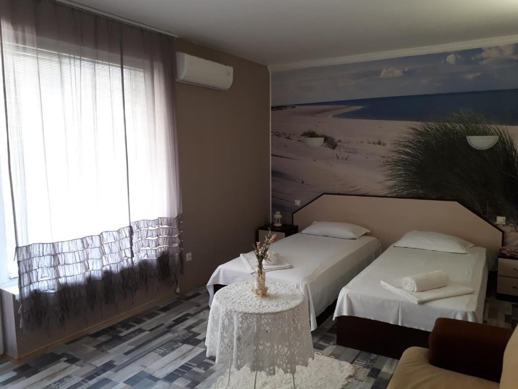a hotel room with two beds and a table in a room at Guest House Orchidea in Pomorie