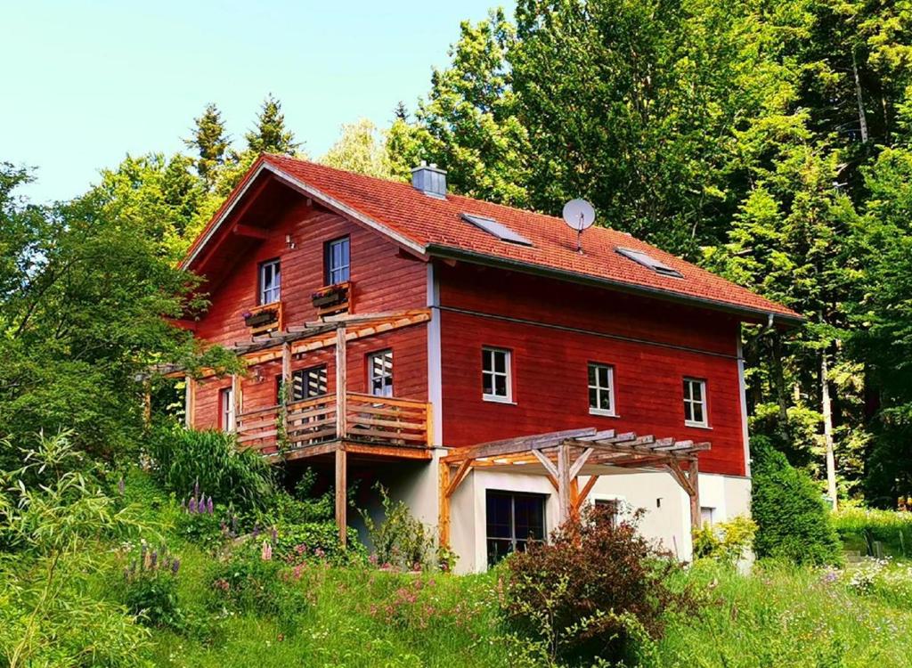 una casa roja en medio de un bosque en Ferienwohnung am Woid, en Waldkirchen