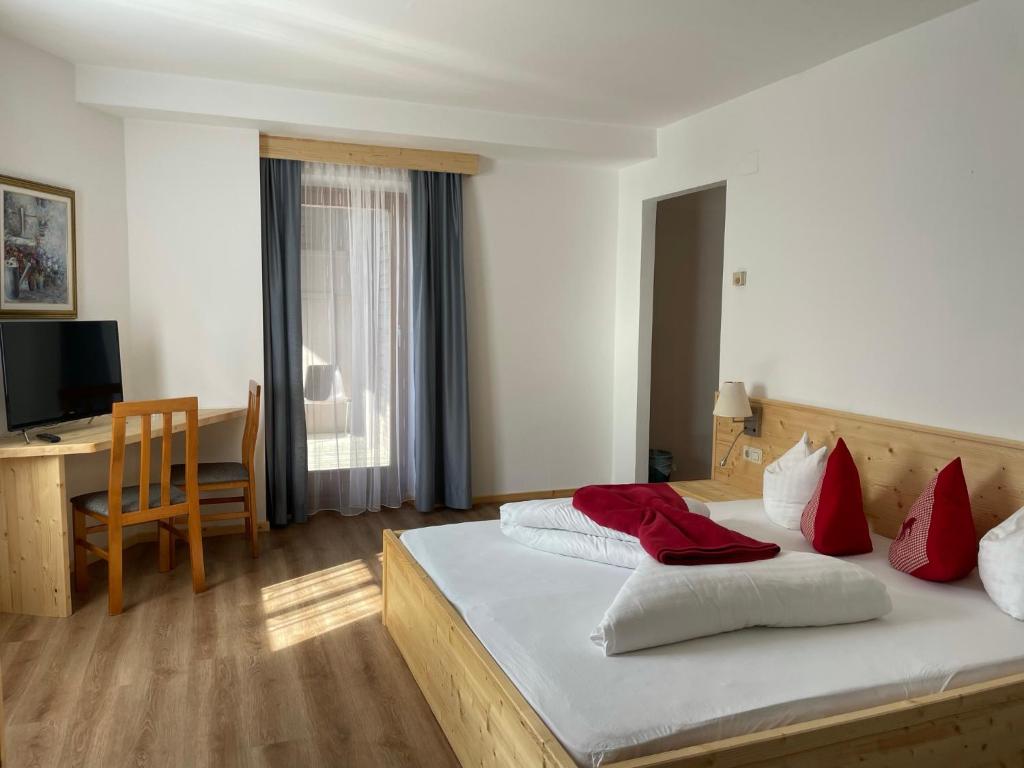 a bedroom with a bed with red and white pillows at Hotel Berghof in Sonnenalpe Nassfeld
