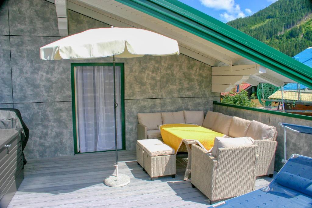a patio with a table and chairs and an umbrella at Apartment Birke 1 - by Alpen Apartments in Bad Gastein