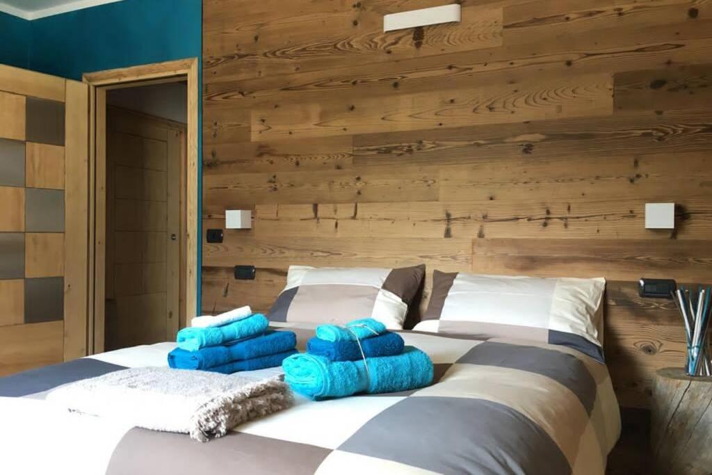 Appartamento a due passi da Bormio في فالديسوتو: غرفة نوم بسرير كبير مع وسائد زرقاء