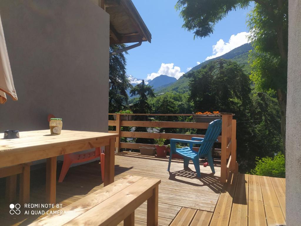 una terrazza in legno con tavolo, sedie e montagne di Clos Bois Joli a Brides-les-Bains