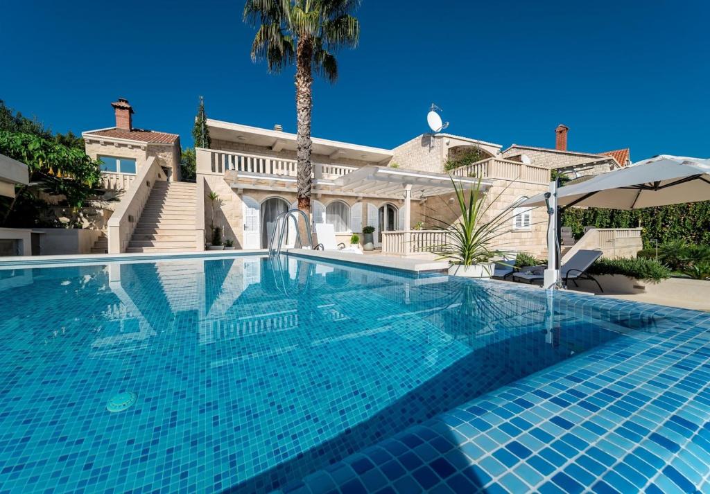 a swimming pool in front of a house at Luxury Villa Stone Castle Brač with private pool on Brač island in Selca