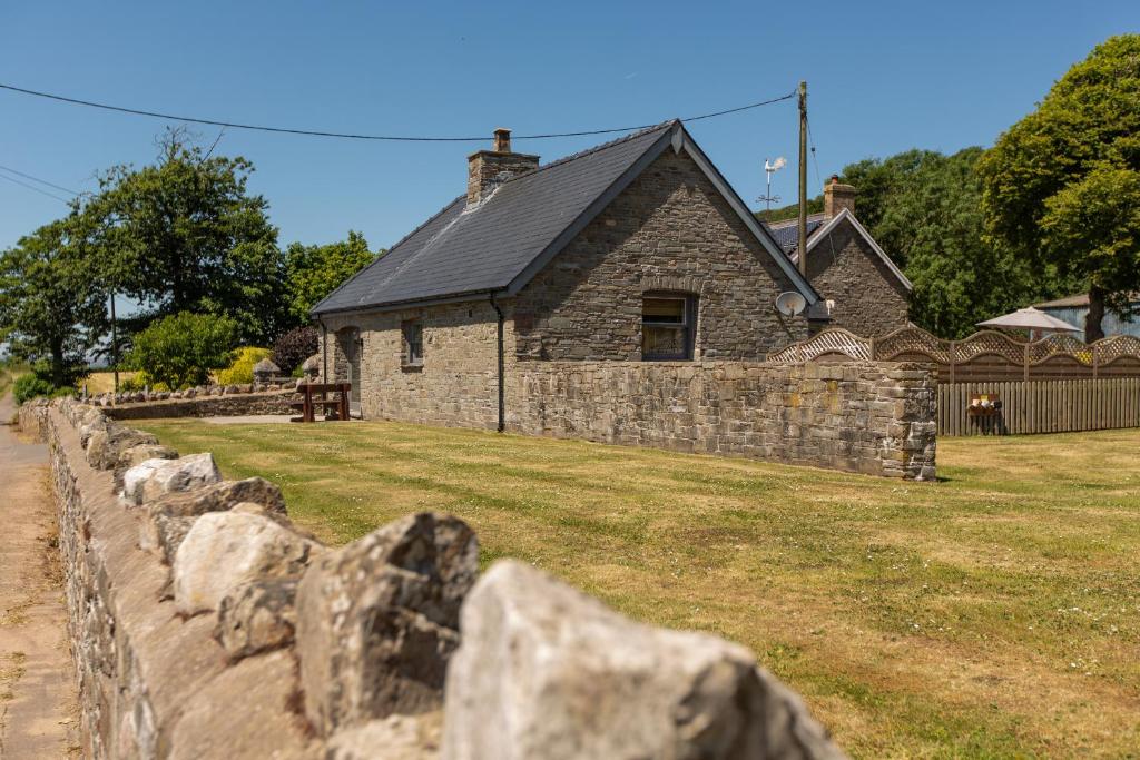 une maison en pierre avec une clôture en pierre devant elle dans l'établissement The Coal House, à Kidwelly
