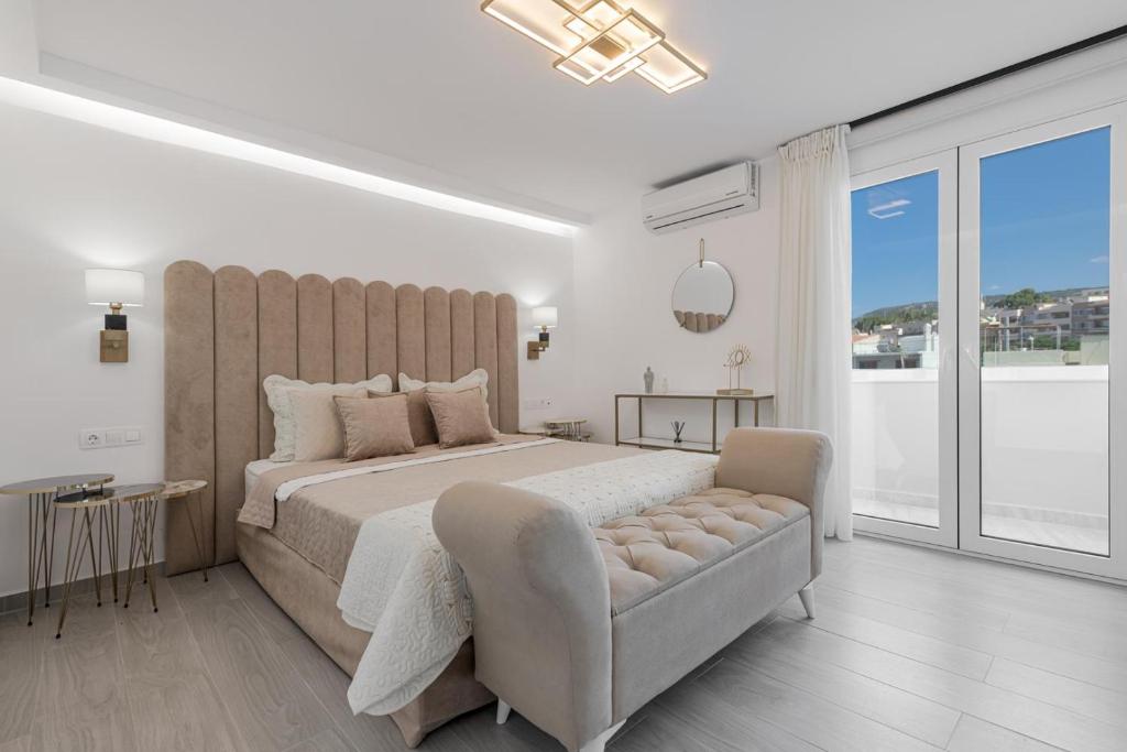 a white bedroom with a large bed and a couch at Diogenis Seaside Suite in Rethymno Town