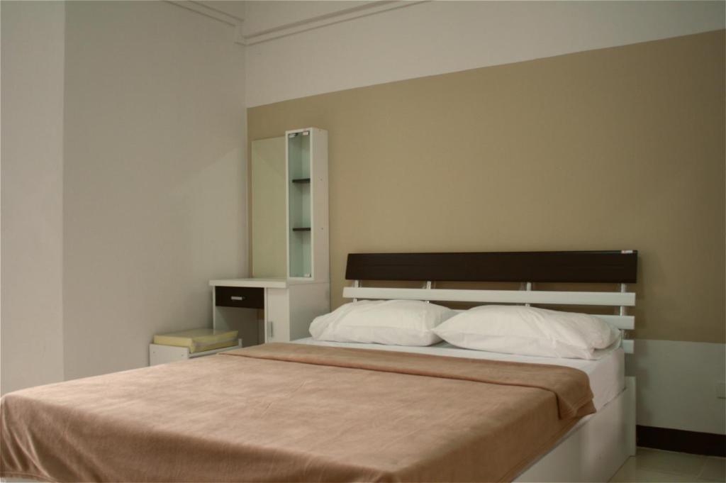 1 dormitorio con 1 cama grande con almohadas blancas en Baanbudsarin Apartment en Sing Buri