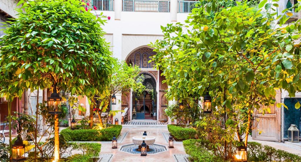 une cour d'un bâtiment avec des arbres et une fontaine dans l'établissement DAR CHIBANIA, à Marrakech