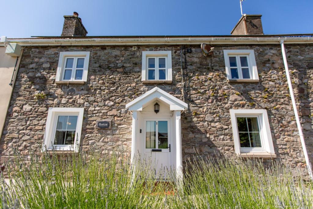 an old stone house with a white door and windows at Hawton in Kidwelly