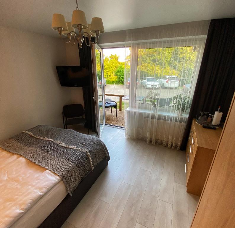 een slaapkamer met een bed en een glazen schuifdeur bij Kopų terasos in Nida