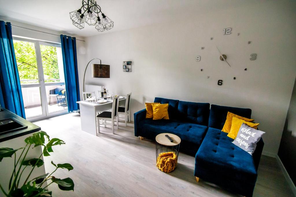 a living room with a blue couch and a clock on the wall at Apartament WHITE in Iława
