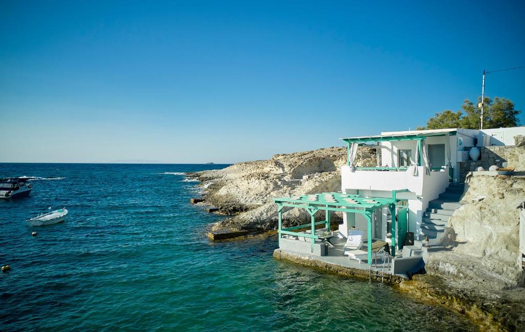 a boat in the water next to a cliff at Terra Mare Suites in Agia Irini Milos