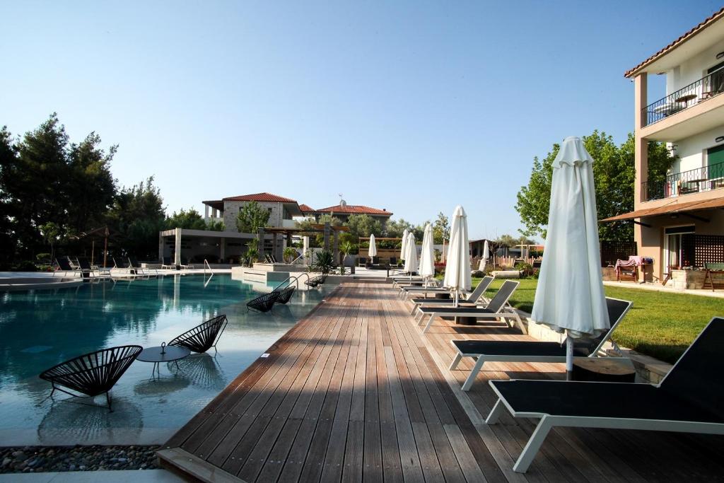 a pool with chairs and umbrellas next to a building at Nostos Hotel in Afitos