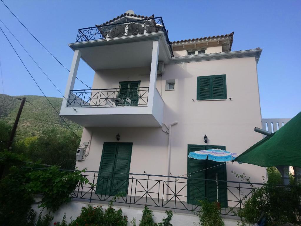 a white building with green doors and a balcony at βίλα Ολγα in Kolónion