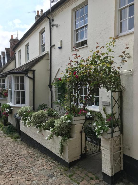 a house with potted plants on the side of it at Beautiful 17th century coach house off high street in Marlborough