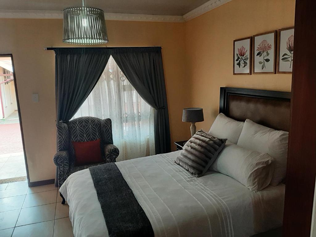 1 dormitorio con 1 cama, 1 silla y 1 ventana en Lesedi Self Catering en Pretoria