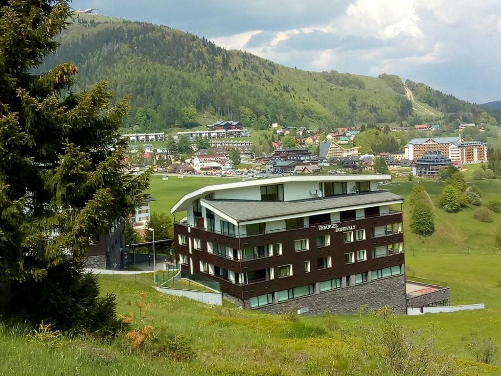 a building in a field with a mountain in the background at Apartman 0204 Donovaly in Donovaly