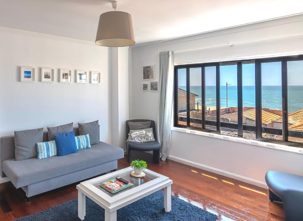 a living room with a couch and a view of the ocean at Espinho Guesthouse - Sea View Apartment in Espinho