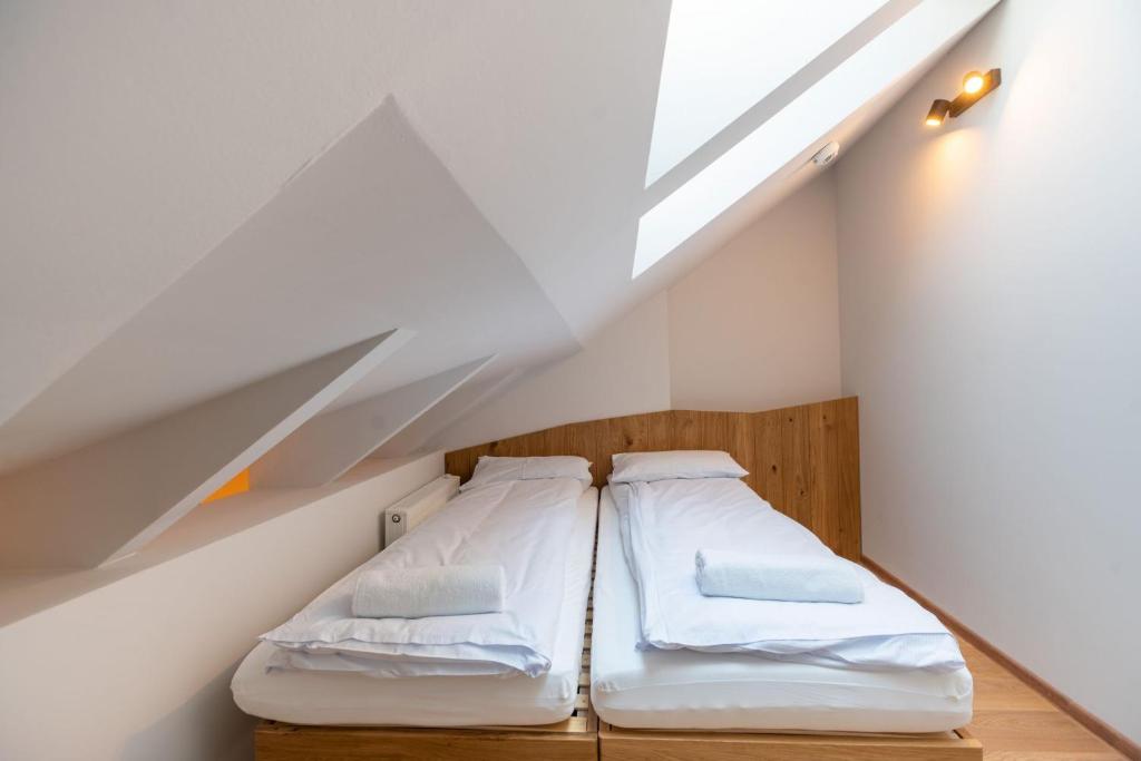 Cozy attic with two single beds under sloped ceiling and skylight, towels laid on beds